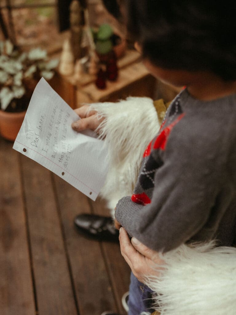 A boy reading his Christmas list to Santa. 