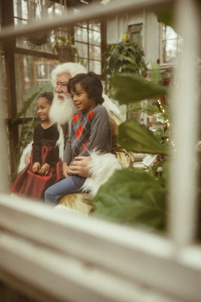 Two young children sitting with Groovy Santa at Das Hinterhaus of Marietta, GA. 