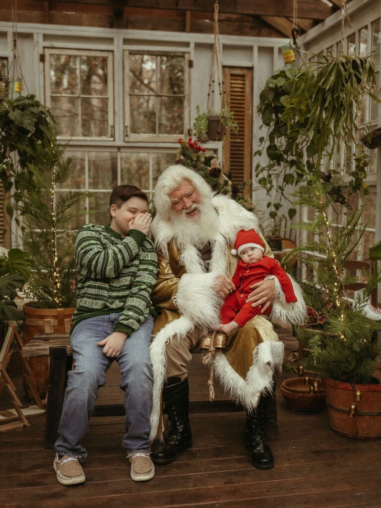 A boy whispers his Christmas wish to Santa who is holding his baby brother at Das Hinterhaus studio in Atlanta. 