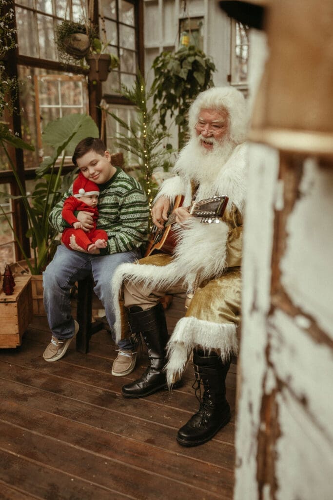 A boy holds his baby brother while The Singing Santa of Atlanta plays them a song at Das Hinterhaus studio.