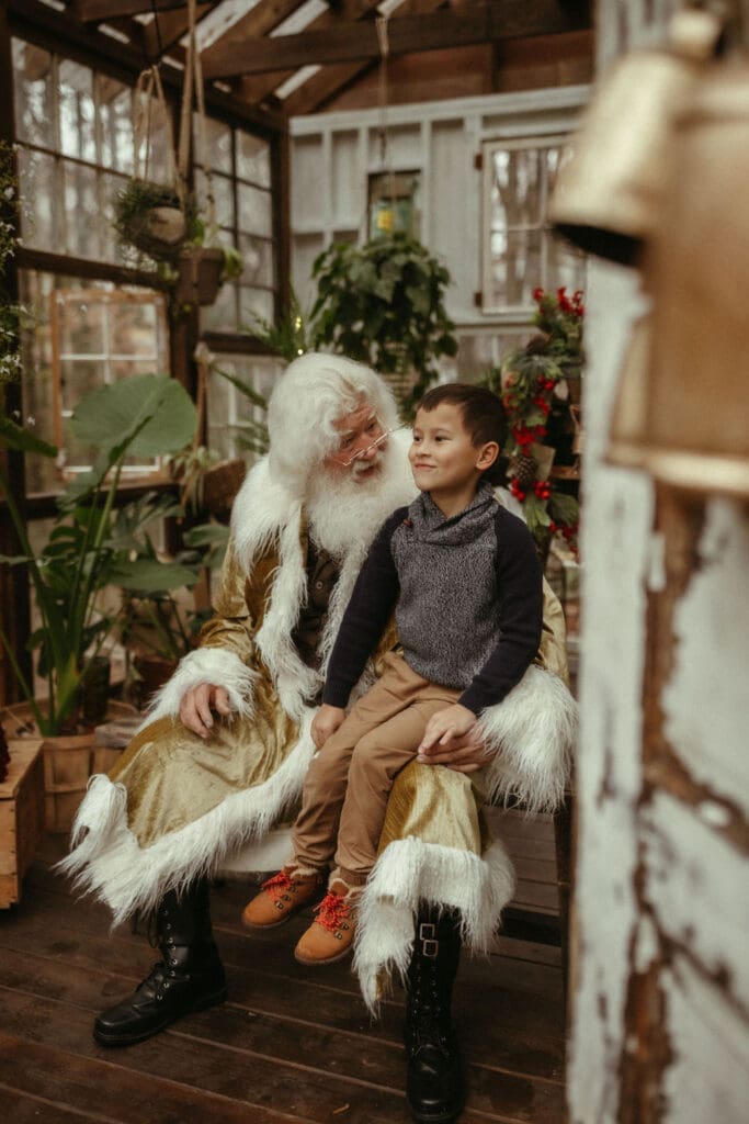 A boy sitting on Santa's lap to tell him all his Christmas wishes. 
