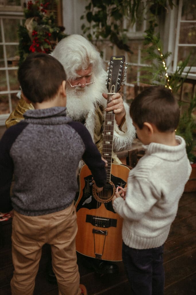 The singing Santa of Atlanta showing two young boys his guitar. 