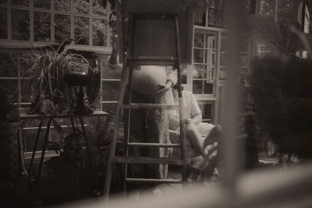 A pregnant mom painting on an easel while her family watches on at Das Hinterhaus in Marietta, GA. 