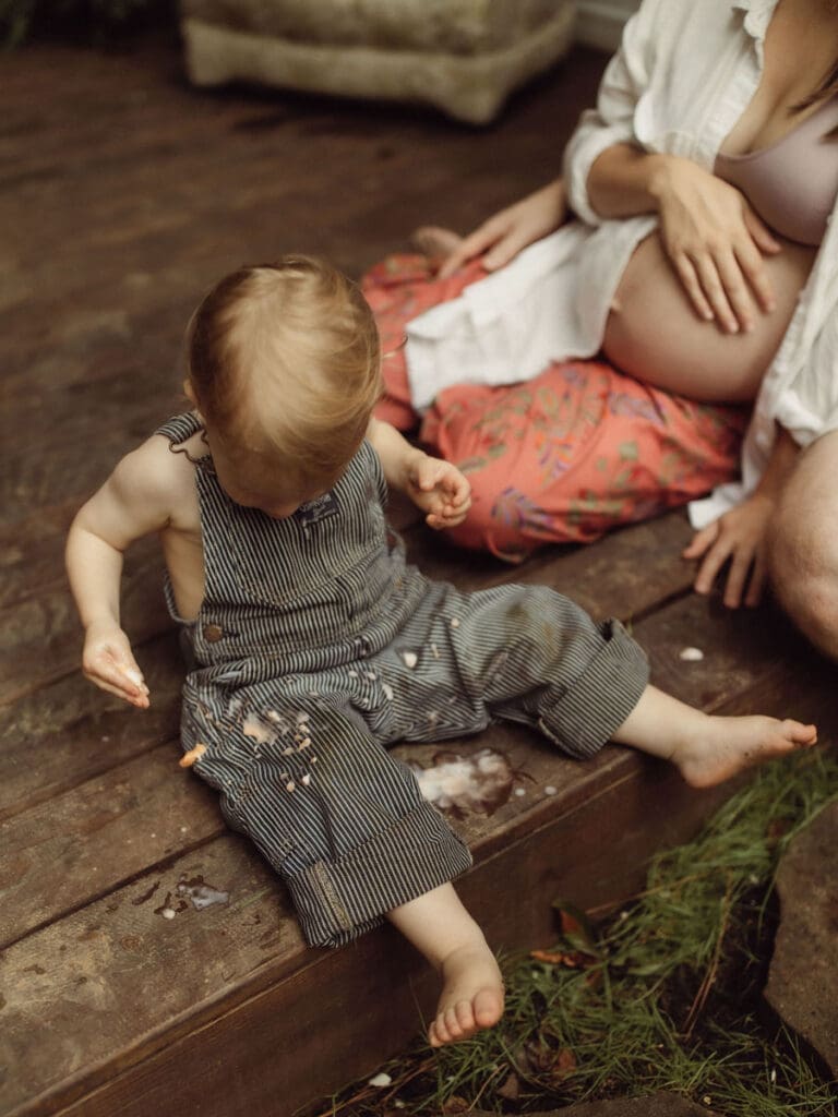 A toddler boy sitting with melted popsicle all over his overalls at Das Hinterhaus. 