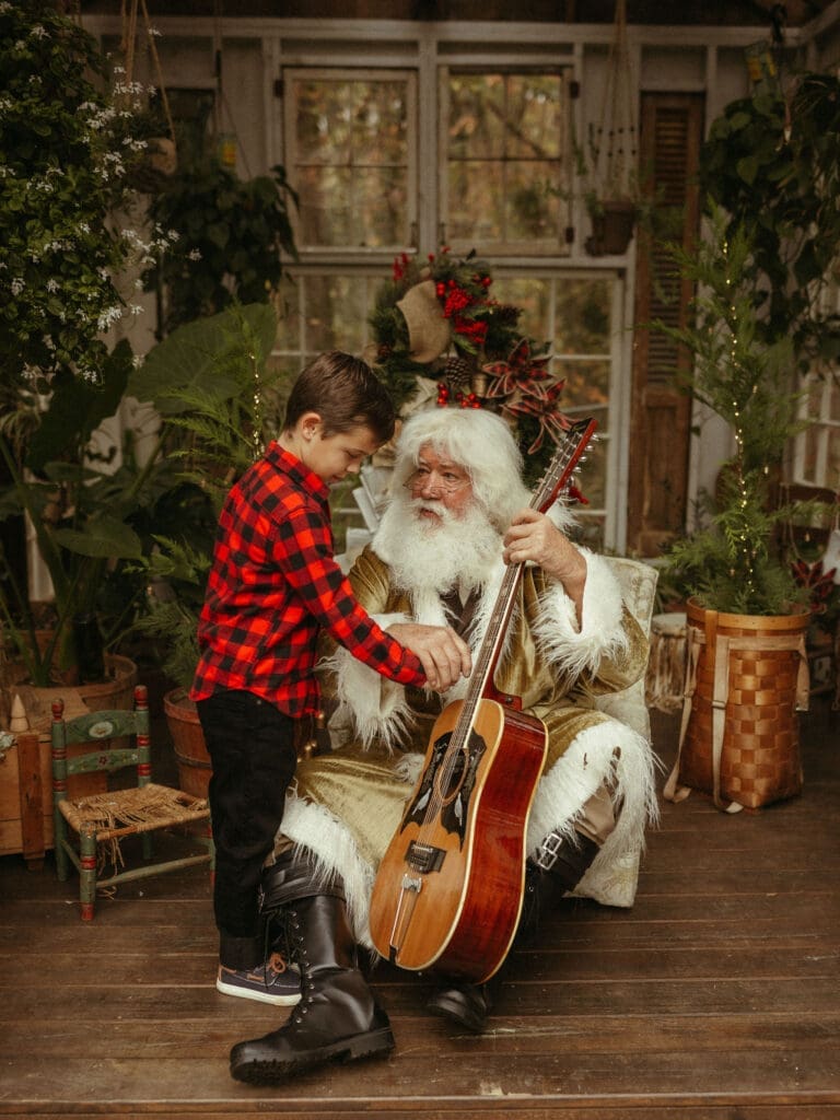 Santa shows a young boy his guitar at Das Hinterhaus in Marietta, GA. 