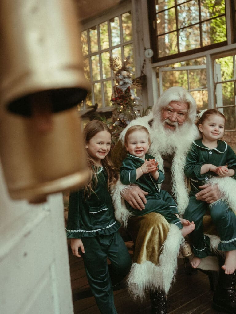 Three young siblings sitting in Santa's lap sharing a laugh at Das Hinterhaus. 