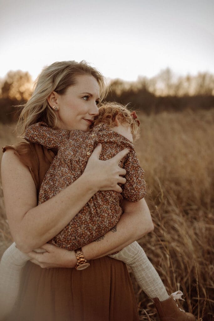 A mom holding her curly red headed  toddler at sunset in Howe, TX. 