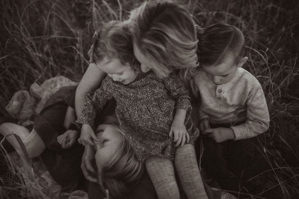 A mom sitting with her three young children. 
