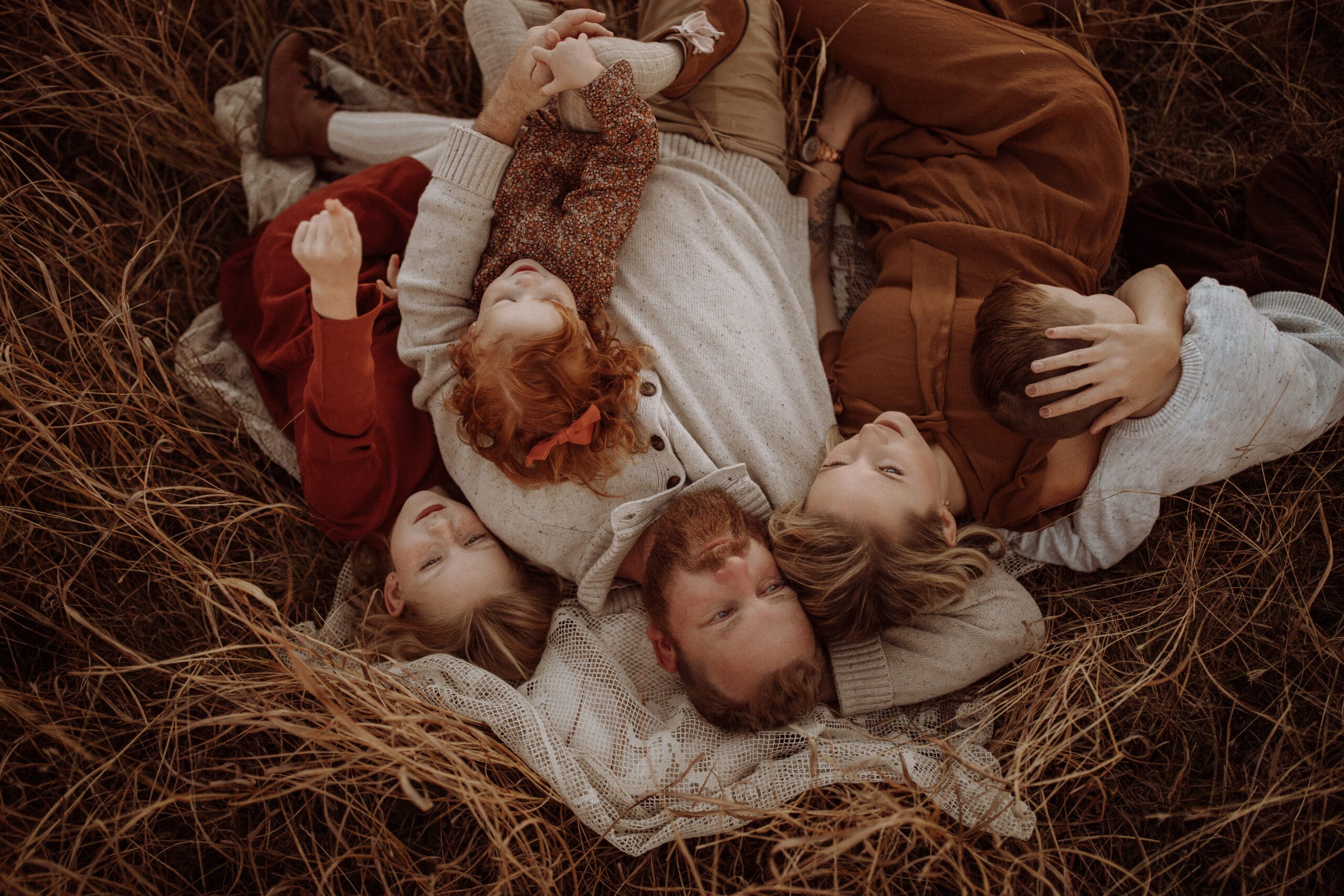 A family of five laying on a blanket in a golden field in Howe, TX.