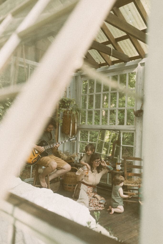 Father playing guitar during a relaxed greenhouse family photography session