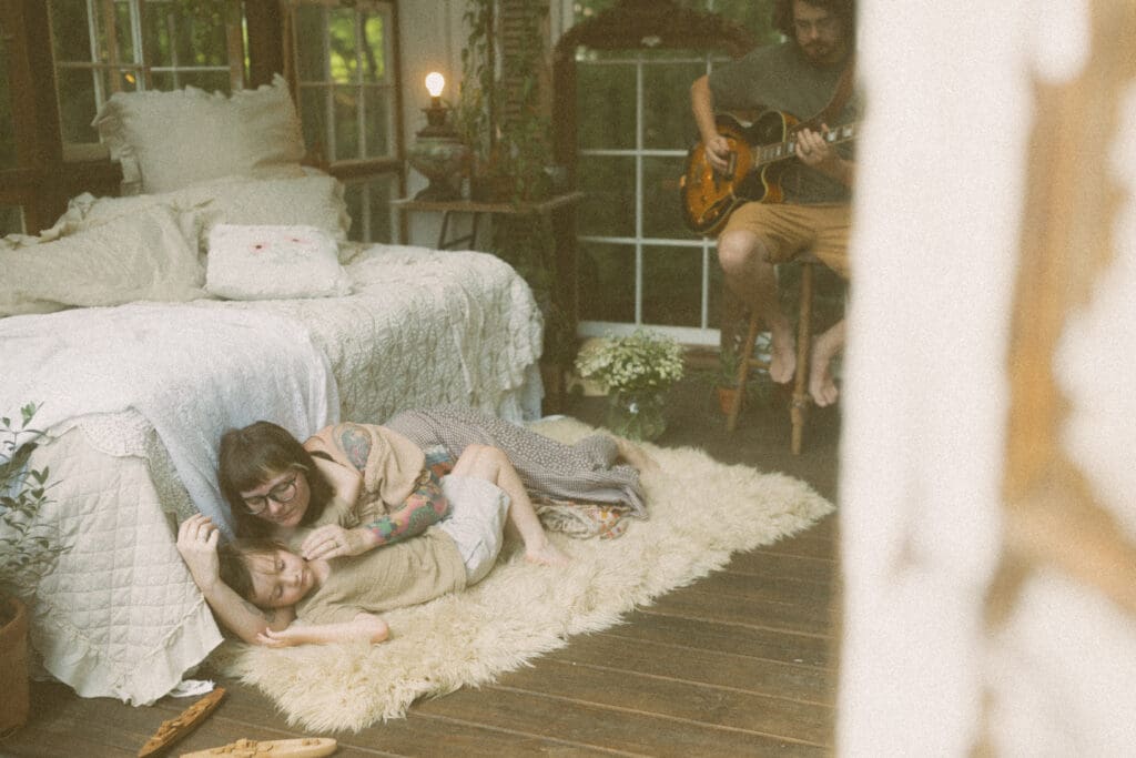 Lifestyle family photography moment with mom and children relaxing on a rug inside a greenhouse