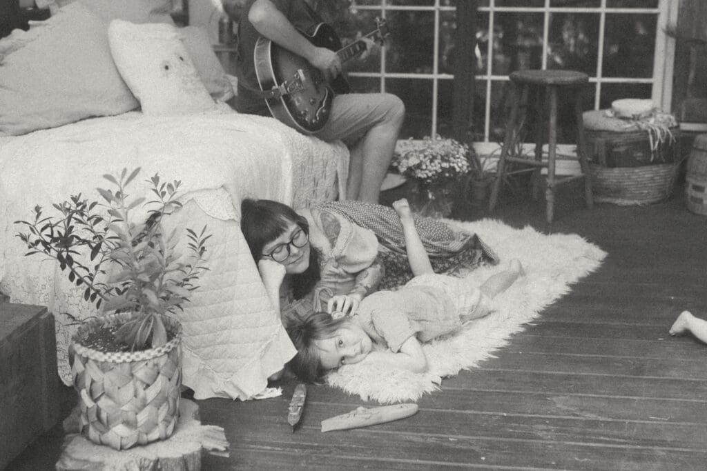Lifestyle family photography moment with mom and children relaxing on a rug inside a greenhouse