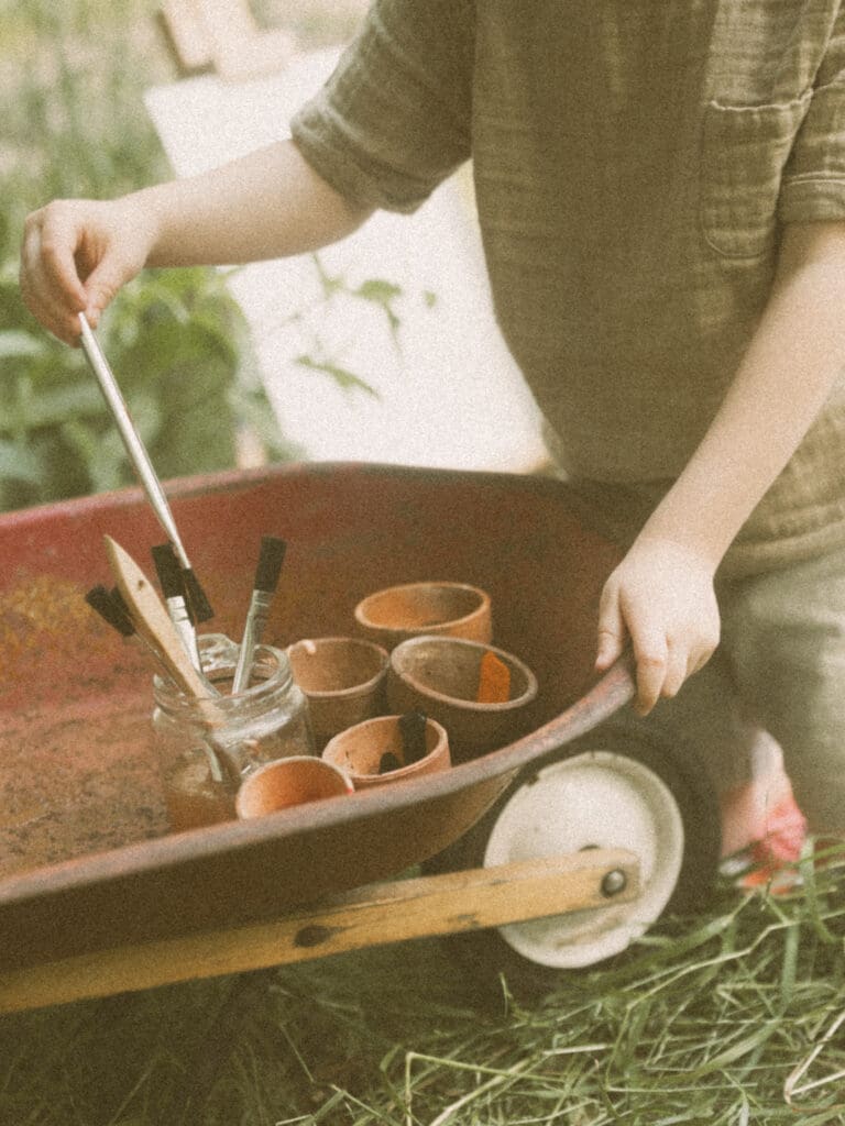 Child-led lifestyle family photography with kids painting during a spring greenhouse session