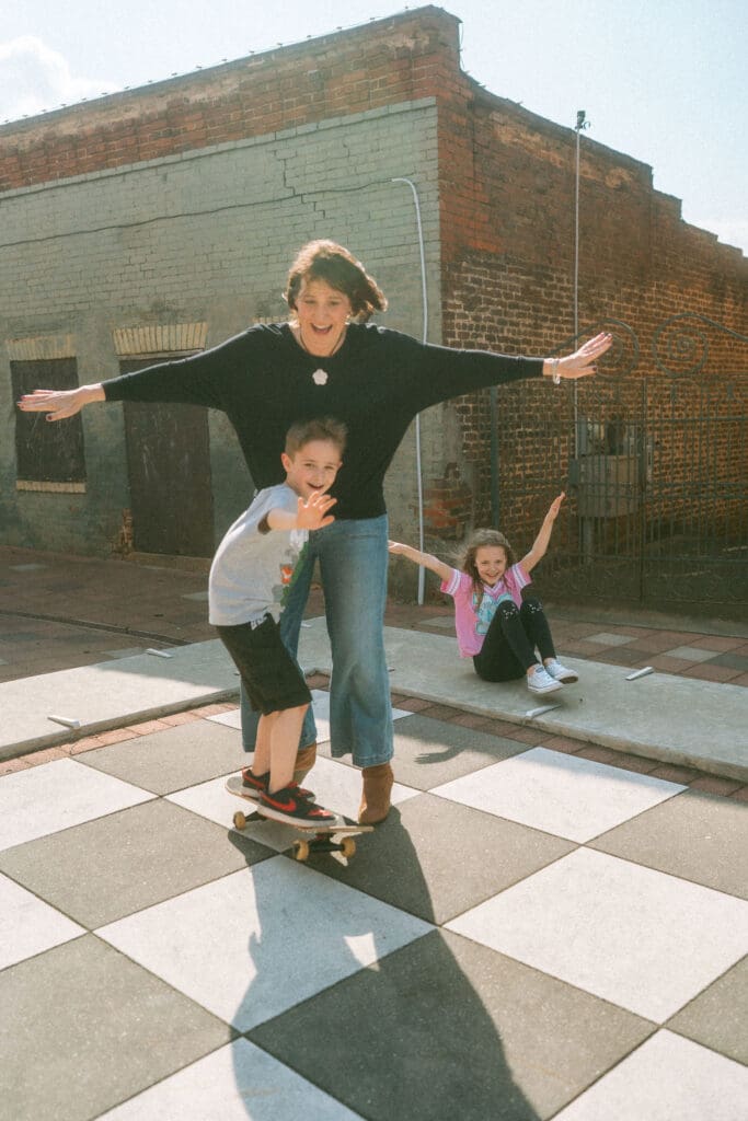 mom and son skateboard in a alley in acworth, ga while big sister sits behind.