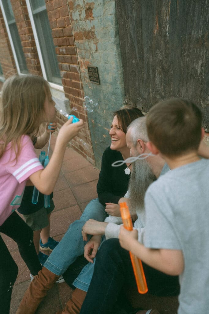 kids in an alley in acworth blwing bubbles at the faces of mom and dad