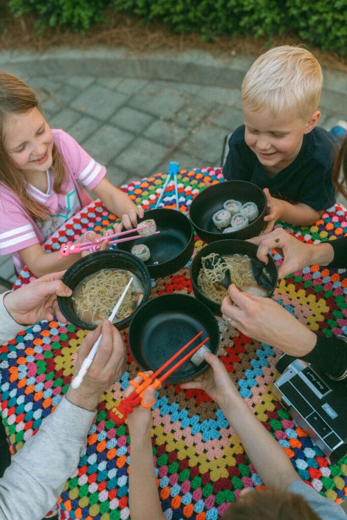 family cheers with their bowls of ramen and sushi