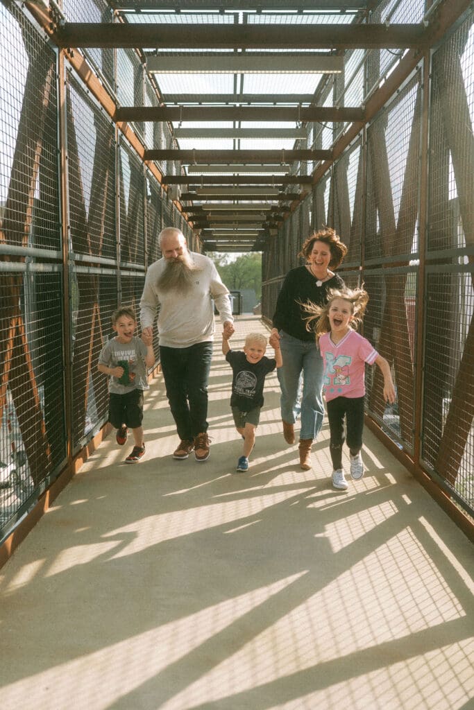 running shot of the whole family on a n enclosed bridge over the railroad in acworth