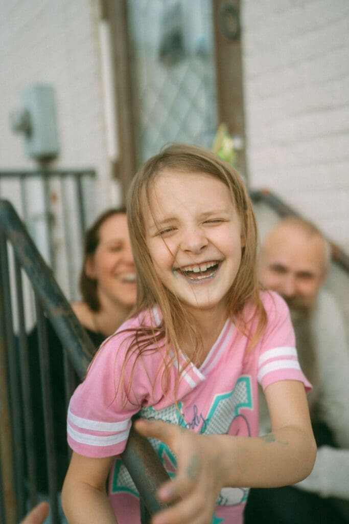 little girl with blue lips from ice cream, squinting and laughing at the camera