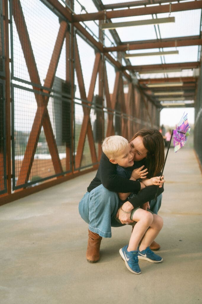 going back across the enclosed bridge and mom stops to snuggle the little boy with his pinwheel